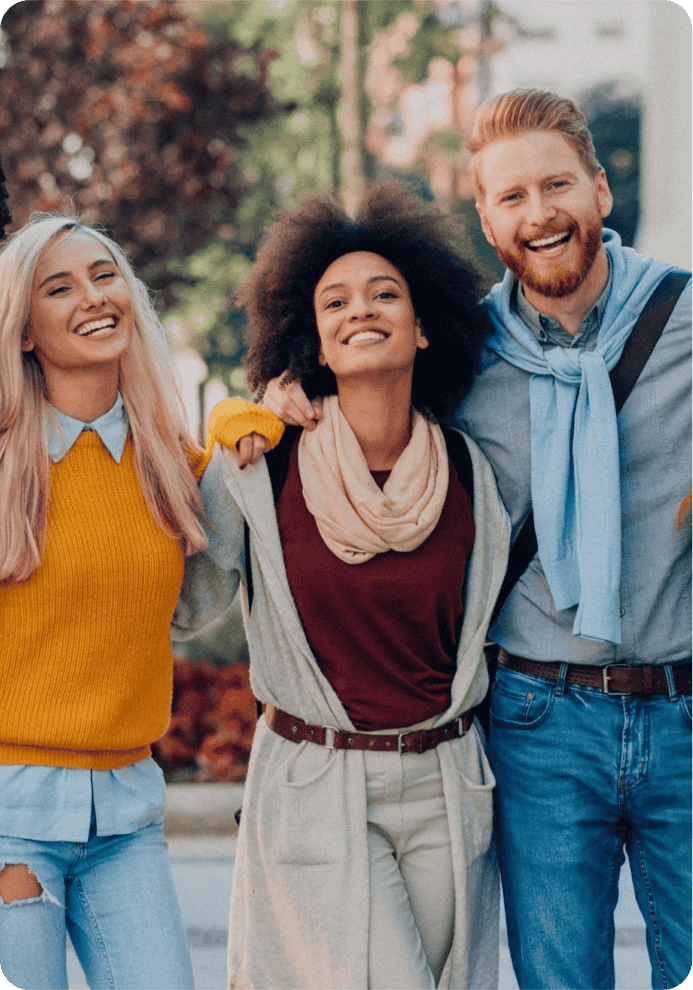 Three smiling friends standing outdoors
