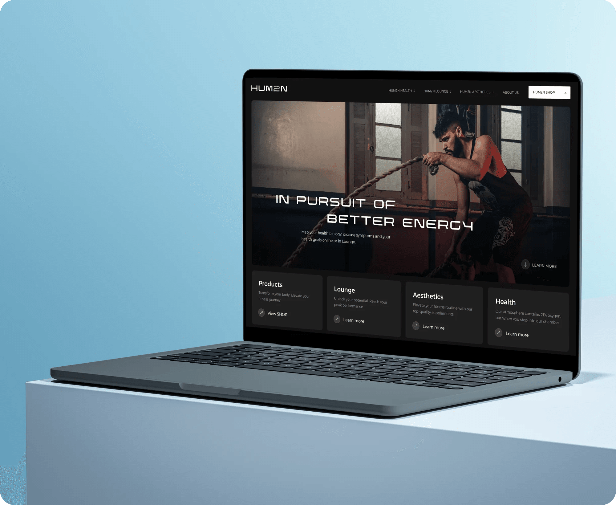 Hum2n clinic website on a laptop: "In pursuit of better energy" with treatment categories.